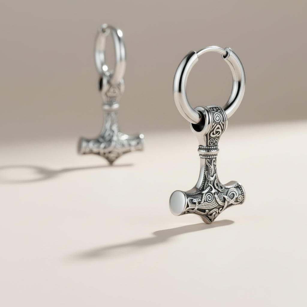 Silver Mjolnir hammer earrings with intricate Norse knotwork designs, hanging from polished hoops.