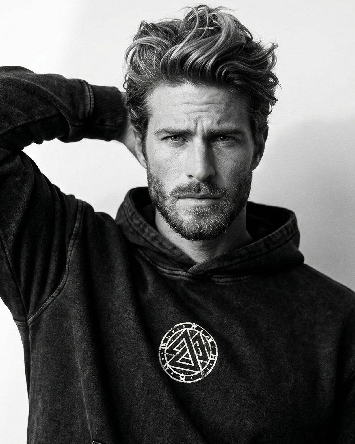 Man in a black distressed hoodie with a white circular Ragnarok Jewelry & Apparel logo.